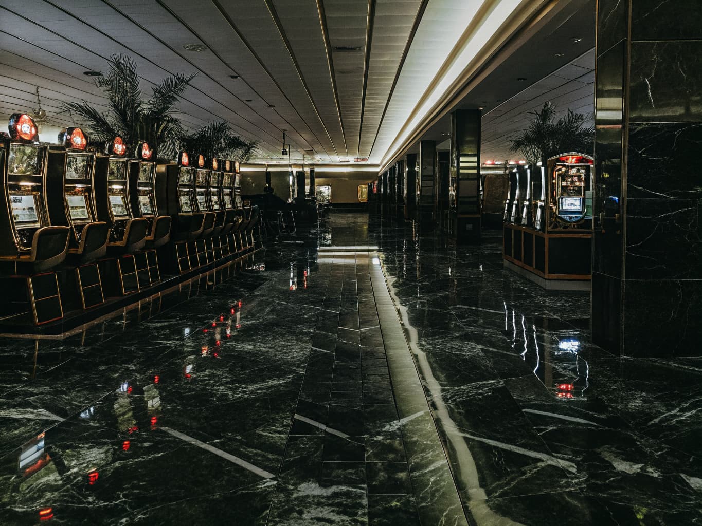 Casino gaming floor with slot machines glowing in red and gold light