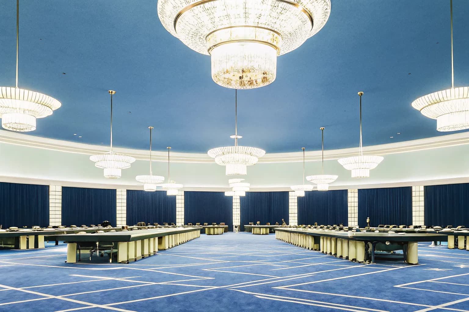 Elegant casino resort gaming floor with card tables and glowing chandeliers