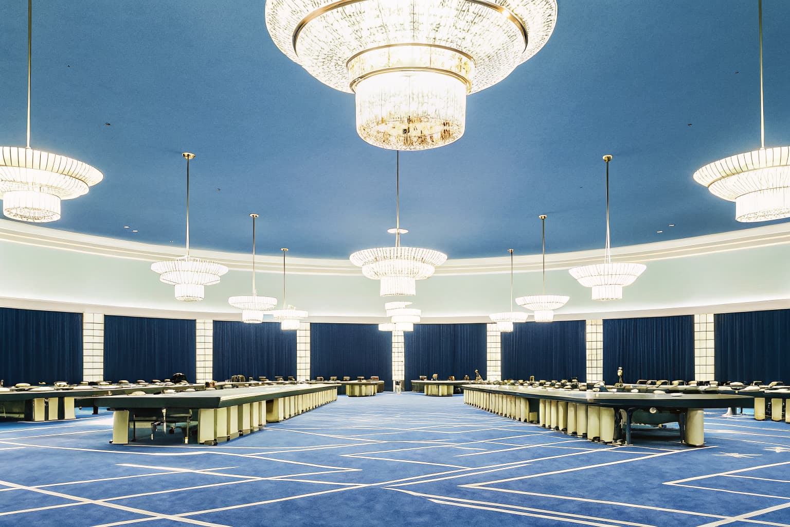 Elegant casino resort gaming floor with card tables and glowing chandeliers