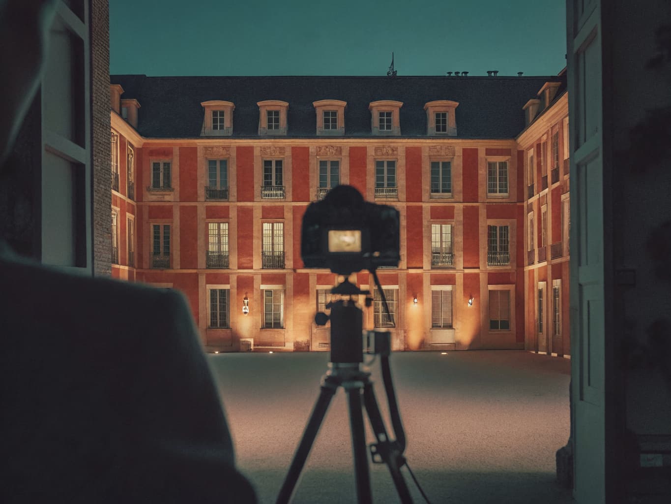 Hotel brand and visual storytelling: camera on a tripod capturing an illuminated boutique hotel courtyard at dusk