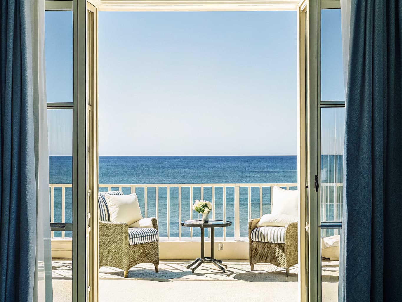 Luxurious resort suite balcony with ocean view and plush furnishings