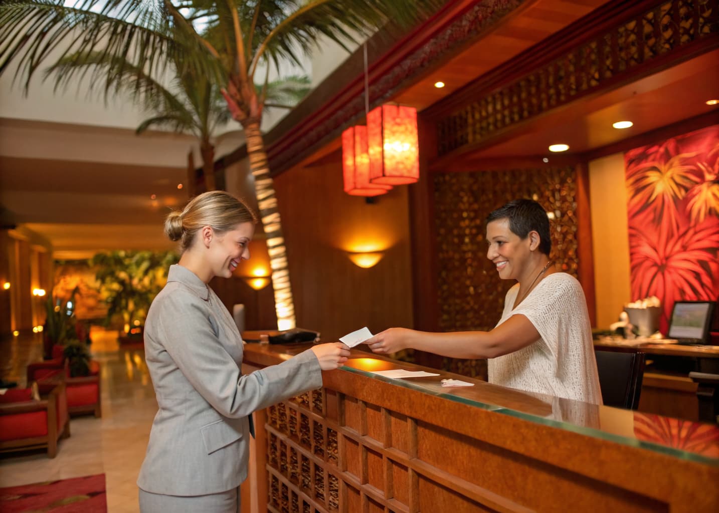 Resort direct booking and OTA strategy: front desk concierge handing a room key to a guest at check-in