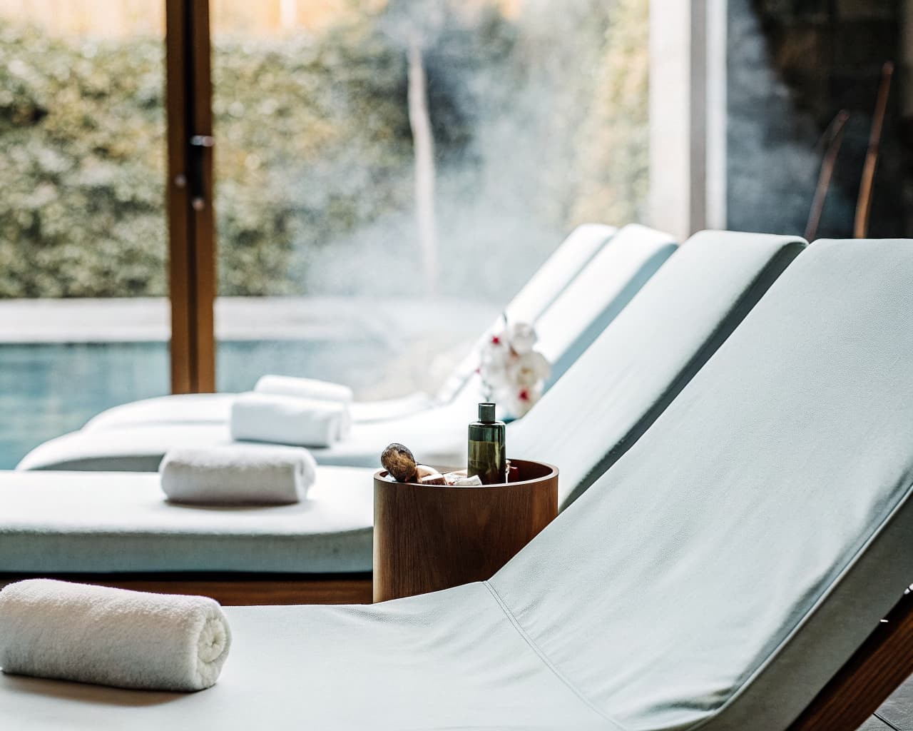Tranquil spa relaxation lounge with poolside chairs and rolled towels